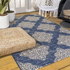 a blue and white rug on the floor next to a potted plant