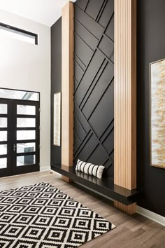 a black and white room with wood accents on the walls, rugs and artwork