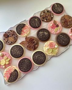 an assortment of decorated cookies and pastries on a platter with pink, brown, and white icing