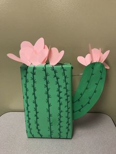 a green box with pink paper flowers in the shape of a cactus on top of it