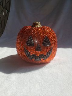 an orange beaded pumpkin sitting on top of a white sheet