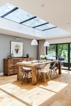 a dining room table with chairs and a skylight in the ceiling above it is surrounded by wood flooring