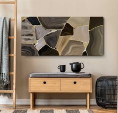 a table with two cups on it in front of a wall hanging over a shelf