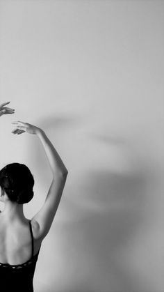 a black and white photo of a woman in a leotard with her arms stretched out