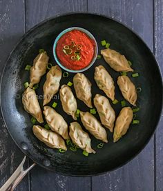 steamed chicken momos in a frying pan with dipping sauce on the side and text overlay