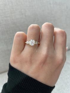 a woman's hand with a diamond ring on top of her finger, showing the side view