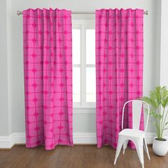 a white chair sitting in front of a window with pink curtains on top of it