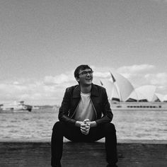 a man sitting on a bench in front of the water