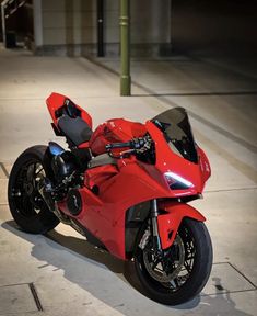 a red motorcycle is parked on the sidewalk