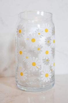 a clear glass vase with yellow and white flowers on the inside is sitting on a marble surface