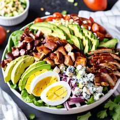 a salad with chicken, avocado, tomatoes, lettuce and bacon