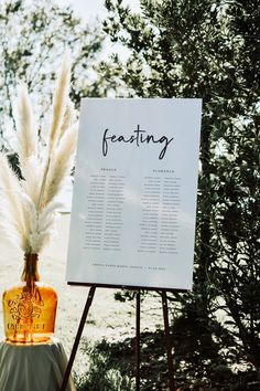 a sign that is sitting on top of a easel next to a vase with some flowers in it