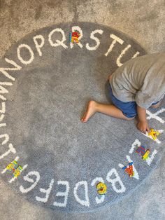 a young boy laying on top of a rug with words written across it in white letters