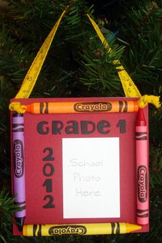 a school photo frame ornament hanging from a christmas tree with crayons on it