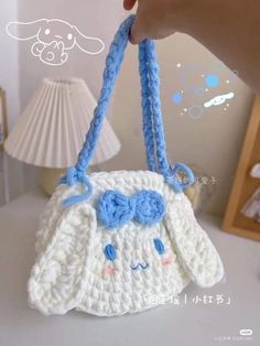 a crocheted purse is being held up by someone's hand on a table