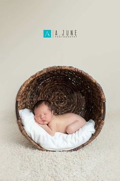 a newborn baby is curled up in a basket