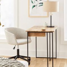 a desk with a lamp and chair in front of a window on a hard wood floor