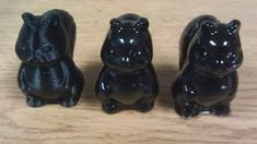 three black ceramic figurines sitting on top of a wooden table