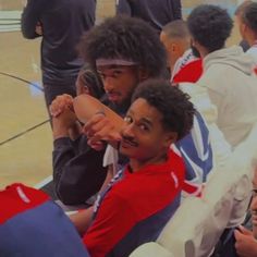 two young men sitting on the floor with their arms around each other