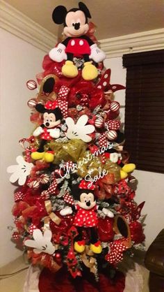 a mickey mouse christmas tree with red bows and minnie mouse decorations on it's top