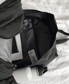 an open laptop bag sitting on top of a white sheet covered bed next to a cell phone