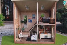 a doll house with furniture and accessories in the front yard, including stairs to the second floor