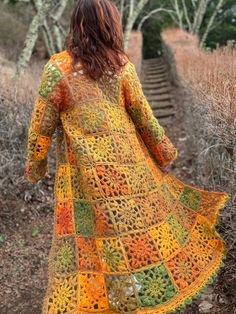 a woman walking down a path wearing a colorful crochet dress