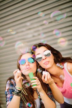 two young women blowing bubbles in the air