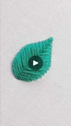 a green piece of yarn sitting on top of a white surface with a black button