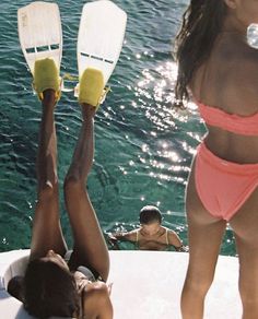 two women in bikinis on a boat with paddles