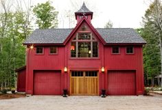 a large red barn with two garages on the front and one above it's doors