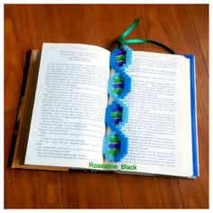 an open book sitting on top of a wooden table next to a string of beads