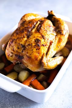 a chicken in a casserole dish with carrots and potatoes