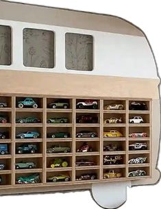 a wooden toy storage unit with cars on it's sides and two windows over the top