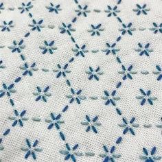 a close up view of some blue and white cross stitchs on a piece of cloth