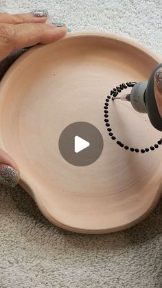 a person using a sharpie marker to paint a bowl with black dots on it