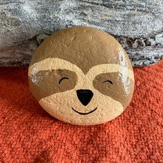 a rock with a face painted on it sitting next to a red rug and rocks