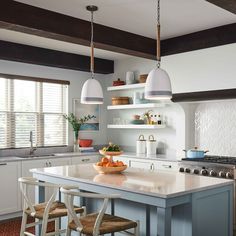 a kitchen with white cabinets and blue island in the center is surrounded by wicker chairs