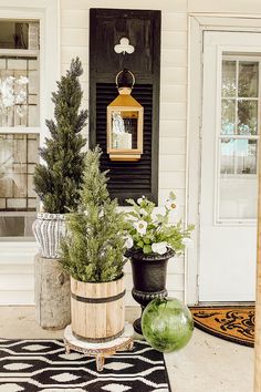 three potted plants sitting on the front porch next to a black and white door