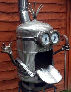 an odd looking metal object with eyes and hands on it's legs, sitting in front of a wooden wall