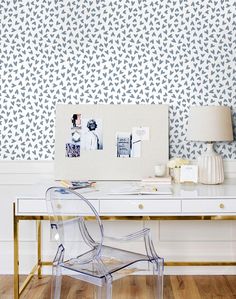 a white desk with a clear chair next to it and a wallpapered background