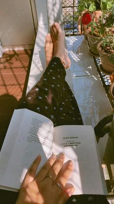 a person is reading a book outside on the patio with potted plants in the background