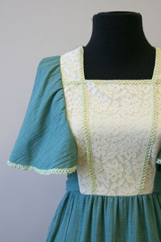 "Description: Vintage 1970s green and cream prairie style maxi dress. Polyester/cotton blend. It has a square neckline, with a lace covered bodice. It has crocheted trim. Short, fluttery sleeves and a ruffled hem. It has attached back ties. Tiered style skirt. Condition: In good condition. No holes. It has a few faint spots. The trim on this dress is very faintly green -- the color bled when it was soaked and attached to the crochet trim. But it is completely even all around, and looks intention Spring Vintage Square Neck Dress, Cottagecore Prairie Dress With Ruffles And Square Neck, Cottagecore Vintage Dress With Ruffles And Square Neck, Spring Peasant Prairie Dress With Square Neck, Vintage Green Square Neck Dress, Retro Fitted Prairie Dress With Square Neck, Vintage Dress With Ruffles And Square Neck, Vintage Dress With Square Neck And Ruffles, Fitted Retro Prairie Dress With Square Neck