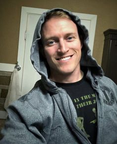 a man wearing a hoodie is smiling for the camera