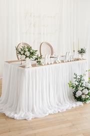 the table is set up with white flowers and greenery for an elegant wedding reception