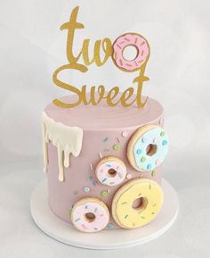 a pink cake with donuts and sprinkles on top that says two sweet