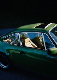 a green car is parked on the side of the road