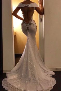 the back of a woman's wedding dress in front of a door with her hand on her hip