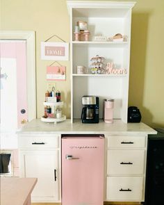 a kitchen with pink appliances and white cabinets