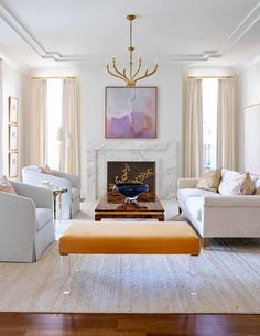 a living room filled with furniture and a fire place under a chandelier above a fireplace